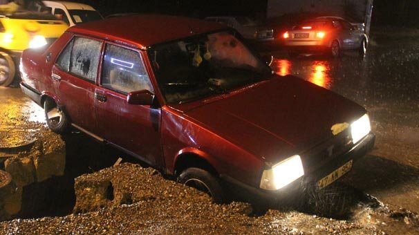 Otomobil yağmur sularının oluşturduğu çukura düştü